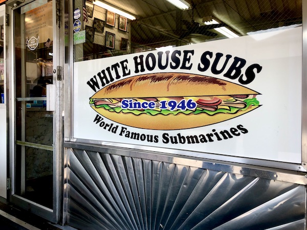 A polished stainless steel entrance to a restaurant with a picture of a sub on Our Pilgrimage to the Jersey Shore