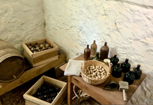 A room with white stucco walls and crates with corks and dark glass jugs for beer at Thomas Jefferson's Monticello