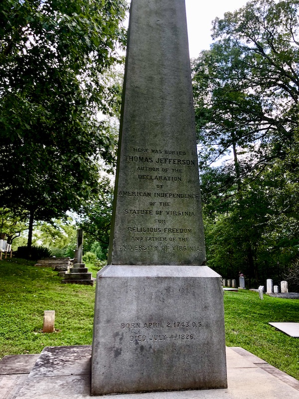 A large stone obelisk flanked by trees is Thomas Jefferson's grave marker at Monticello.