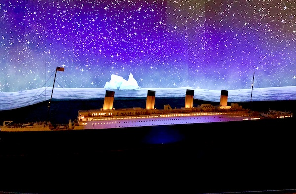 A replica of Titanic, dark sky with stars and an iceberg in the distance.