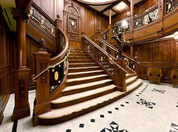 A dark wood staircase with white steps and white and black floor aboard Aboard Titanic Pigeon Forge TN