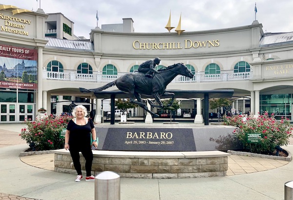A white building with a statue of a racehorse in front at Churchill Downs Louisville Kentucky