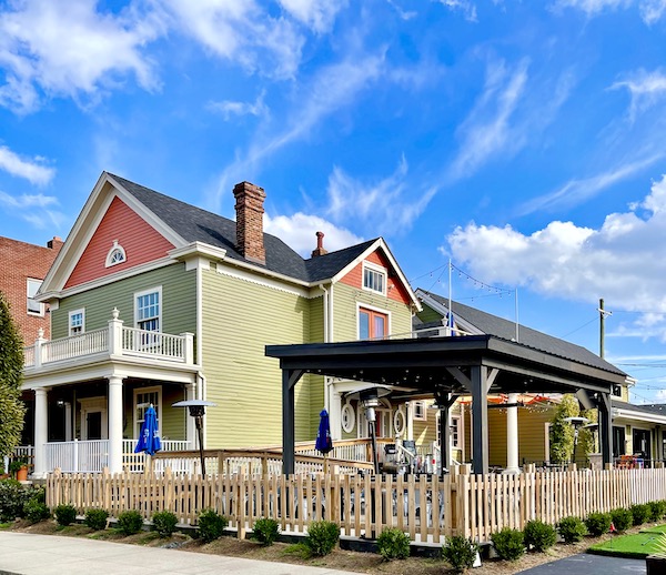A yellow and coral home with porch and garden.