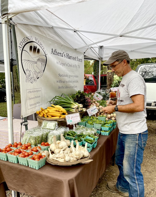 A man standing in front of a table of fresh produce at the Farmers Market Nashville TN
