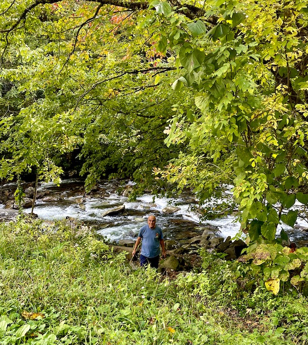 A man in a navy sweatshirt coming up from the creek in the woods at Great Smoky Mountains National Park