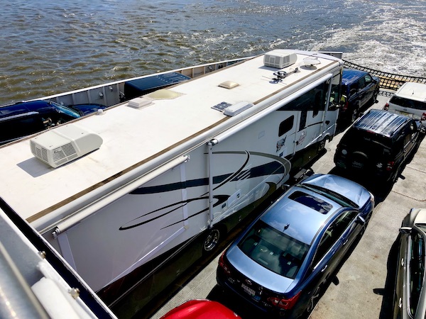 An RV and a car packed in tight on the ferry.