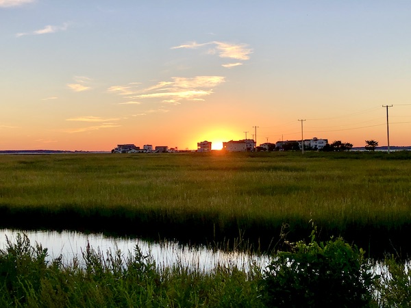 The setting sun created an orange halo as it set behind the RVs, lawn and lake.