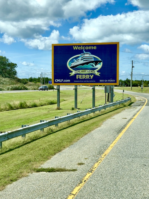 A sign on the side of a road welcoming us to the Cape May-Lewes Ferry.