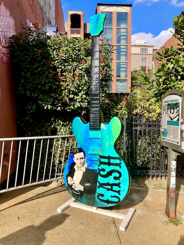A turquoise guitar displayed on the street in honor of Johnny Cash.