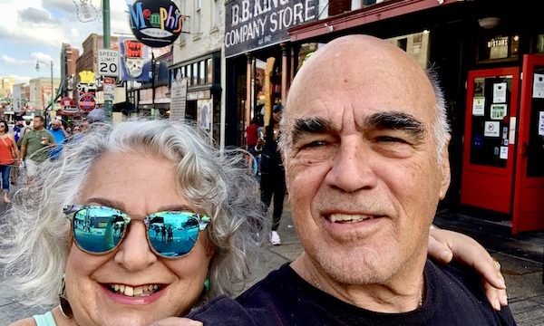 A silver haired woman in sunglasses and a man in a black T on Beale Street in Memphis Tennessee