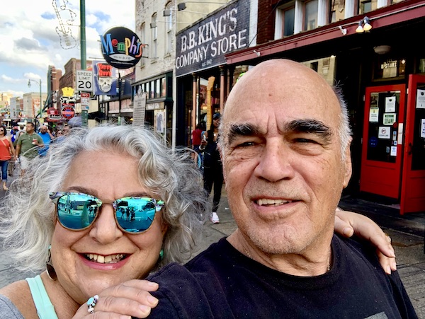 A silver haired woman in sunglasses and a man in a black T on Beale Street in Memphis Tennessee