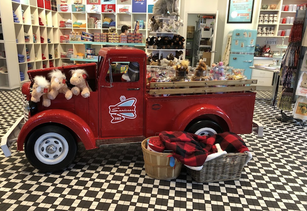 A vintage red pickup truck filled with stuffed animals and shelves with souvenirs at Sunliner Diner Pigeon Forge TN