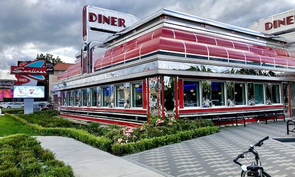 A classic diner with red trim and landscaping in front.
