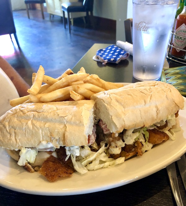 A beige plate topped with two halves of a sandwich and fries.
