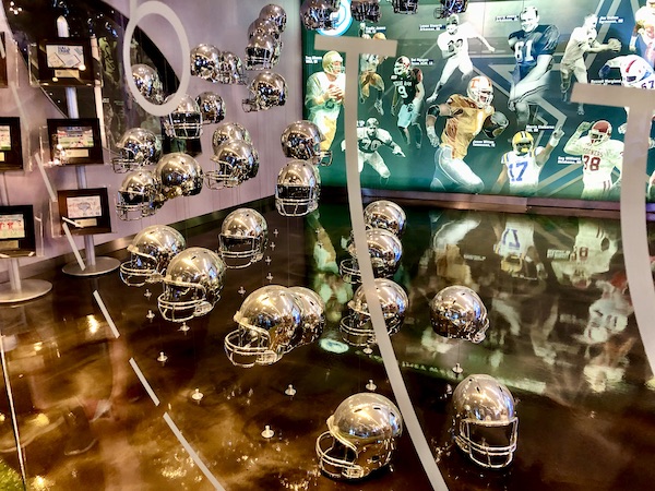 A series of mini gold football helmets suspended from the ceiling seen on our Dallas Cowboys Stadium Tour