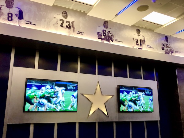 A wall of lockers, 2 TVs and photos of famous Cowboys players through the years.