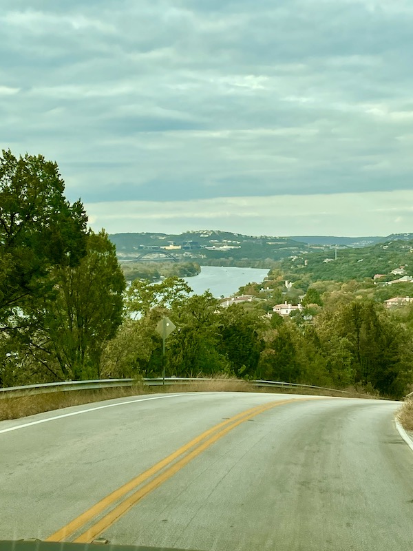 A highway crest with lake and landscaping coming into view.