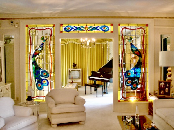 A living room with upholstered chairs and gold drapes. There's an old TV and a black Grand Piano at Graceland Home of the King