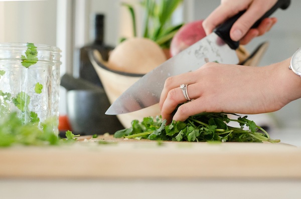 A woman's hands holding and cutting vegetables with a chef's knife from How to be Mindful of What Goes into Your Food