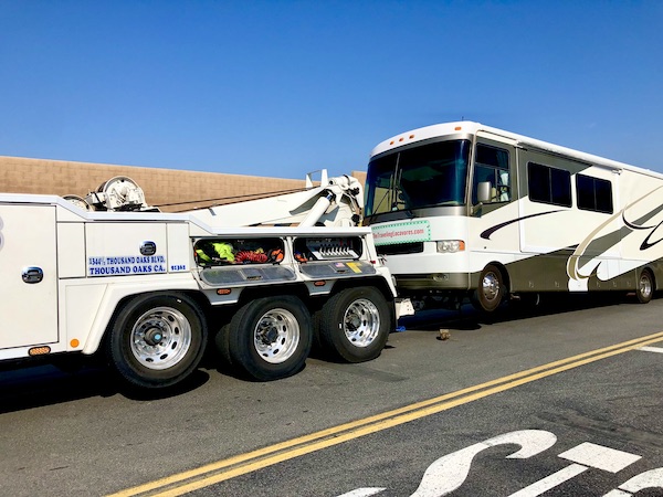 A white RV has its front wheels lifted off the ground.
