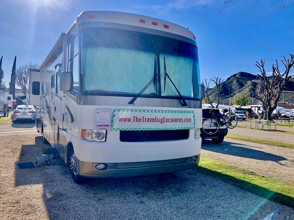 A white and beige RV parked at an RV park site after getting new brakes for Ladybug