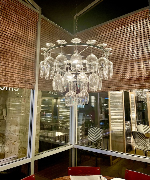 A chandelier made of upside down wine glasses hangs in