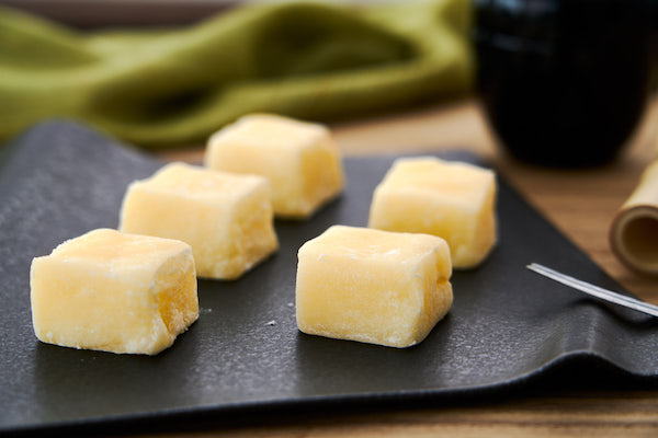 A black platter topped with 5 squares of butter mochi from The 6 Principles of Baking