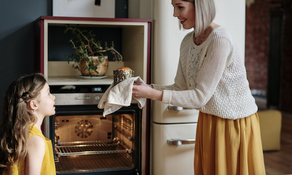 A woman presenting a small cake to her daughter from The 6 Principles of Baking