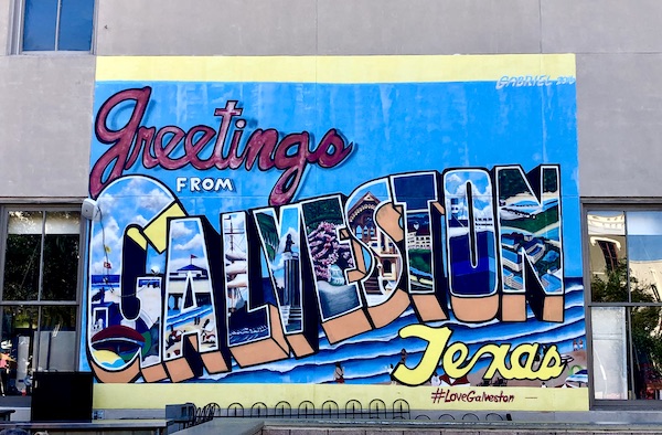 A colorful mural on a building says Greetings from Galveston Texas