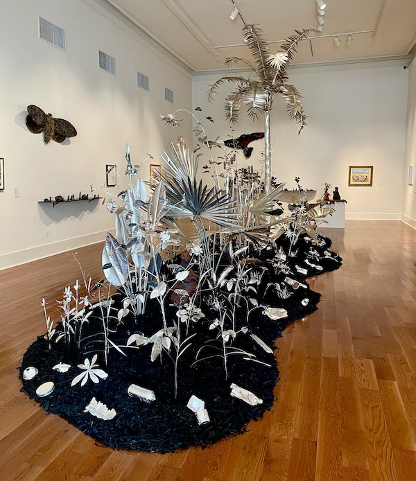 A black island with aluminum palms and other plants.