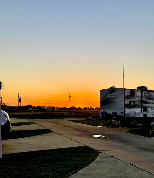A blue sky with orange and yellow at the horizon behind an RV park in Wonderful Galveston Island Texas