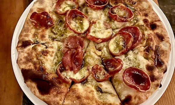 A whole pizza topped with crispy edged salami slice and cheese.