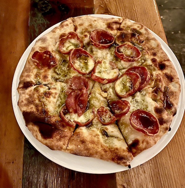 A whole pizza topped with crispy edged salami slice and cheese.