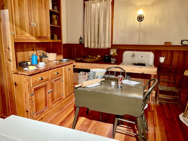 Wood cabinets and olive painted drop leaf table and white porcelain sink at the Grace Museum.