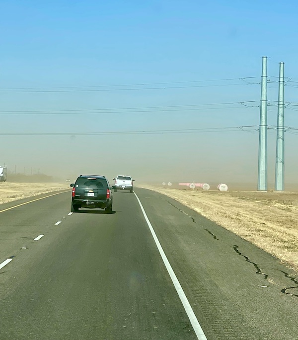 Cars on a highway driving through a wind and dust storm.