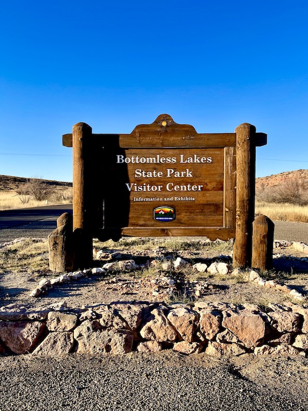 A brown wood sign welcoming you to Bottomless Lakes State Park Roswell NM