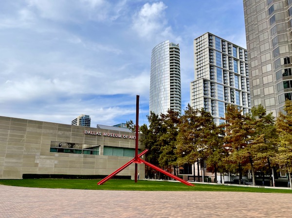 A contemporary building on left, on right are trees and tall glass office buildings.