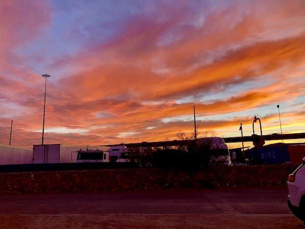 An orange and purple sunset behind and RV park.