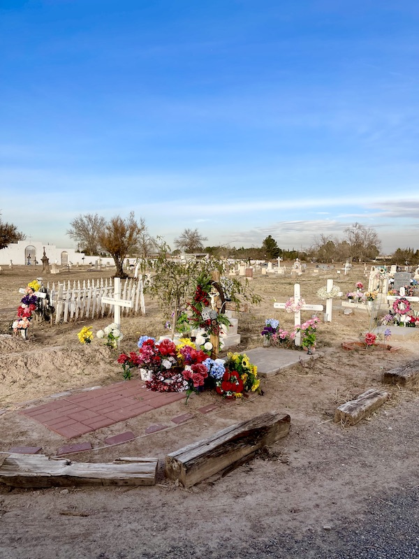 A cemetery with flower and white crosses at gravesites along the El Paso Texas Mission Trail