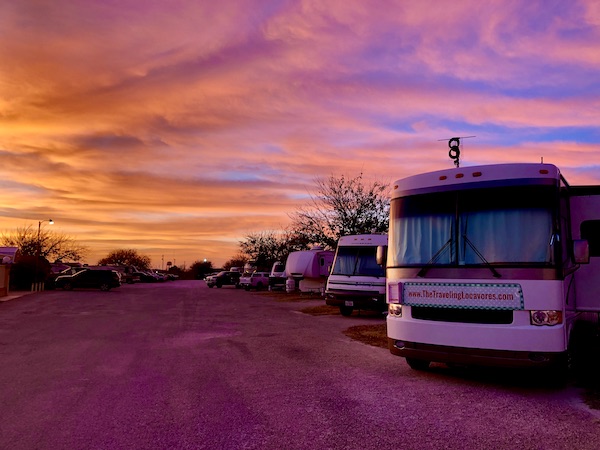 A vivid sunset sky of pink, yellow, purple and orange behind our RV in Abilene