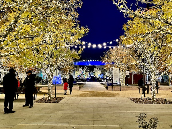 Lit trees, people walking and strings of white lights in a park in downtown El Paso TX.