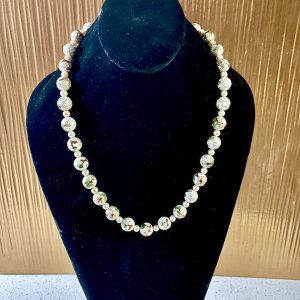 White bead necklace on black neck stand display.
