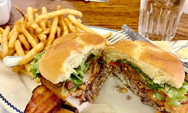 An oval plate topped with the Fred Harvey Burger Grand Canyon AZ, and French fries.