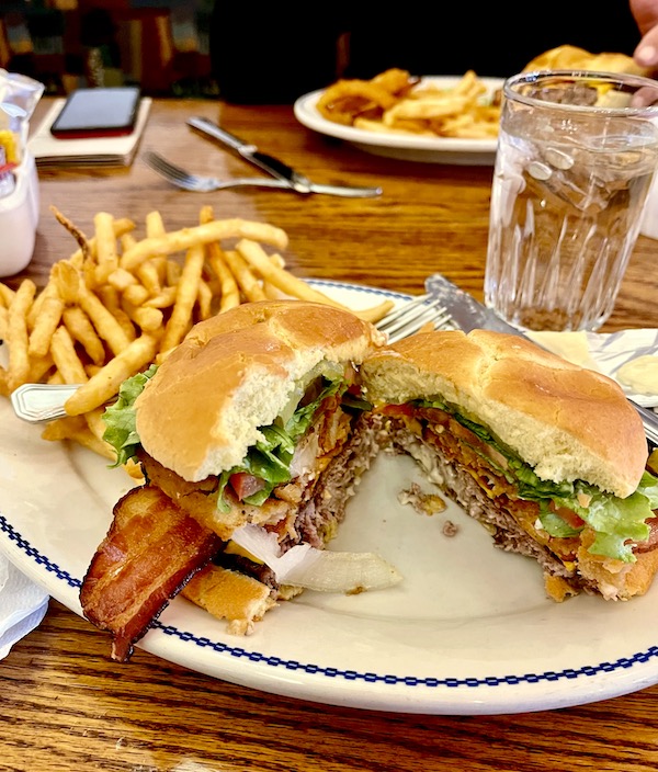 An oval plate topped with the Fred Harvey Burger Grand Canyon AZ, and French fries.