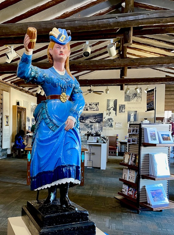 A wood statue of a woman in blue in the gift shop of Fred Harvey Burger Grand Canyon AZ