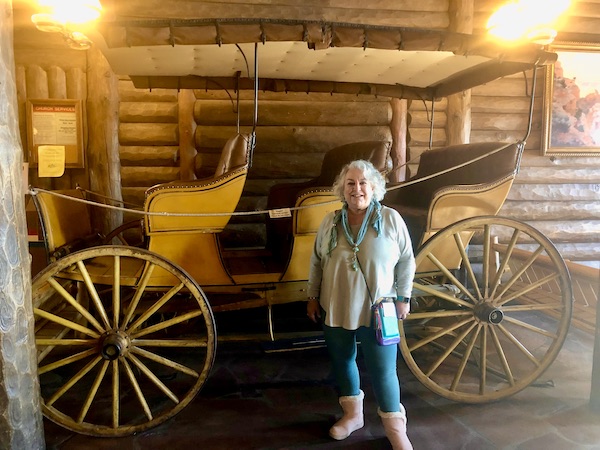A woman in pink boots standing in front of a surrey at Fred Harvey Burger Grand Canyon AZ