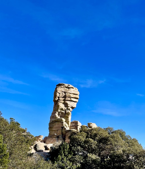 White rock formation at the top of a mountain looks like a man.
