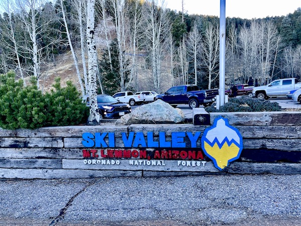 A parking lot and huge blue and red sign for Ski Valley.