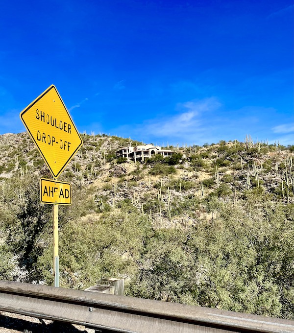 A white house with lots of windows sits on a mountainside among lots of tall cactus on our way up Mount Lemmon Tucson AZ