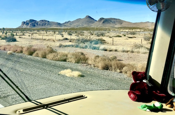 Desert and mountains seen through the windshield of an RV.